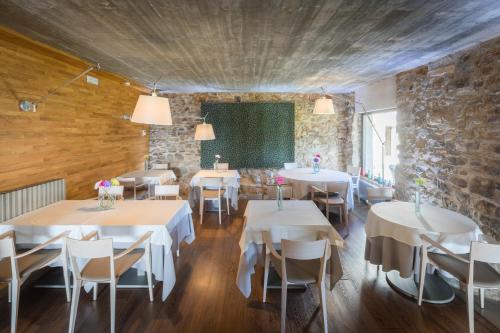圣胡安-德拉斯阿巴德萨斯普兰斯格劳酒店的一间设有白色桌椅和石墙的餐厅
