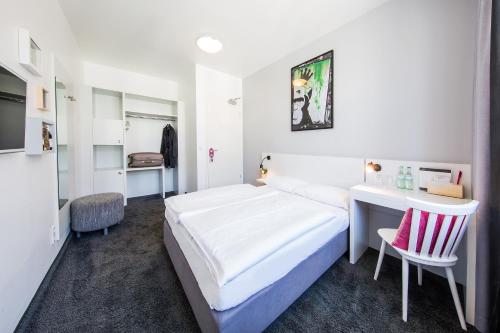 柏林柏林科尔马米特酒店的白色卧室配有床、书桌和椅子