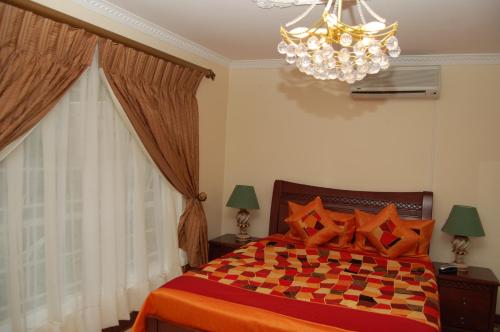 哈博罗内Falcon Crest Suites的一间卧室配有一张床和一个吊灯