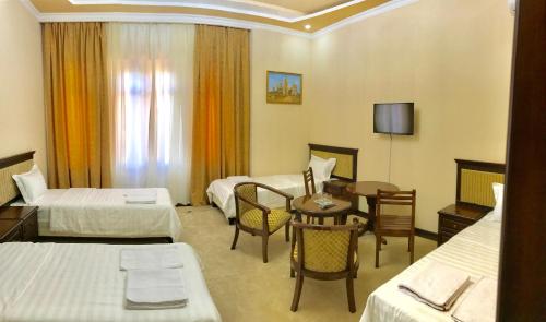 撒马尔罕萨马尔罕穆扎法尔酒店 的酒店客房设有两张床和一张桌子。
