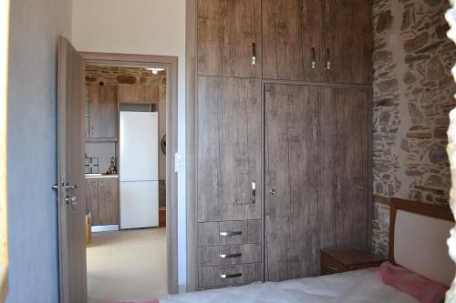 KeramotíCaptain Nikolas的一间卧室配有木制橱柜、一张床和一台冰箱。