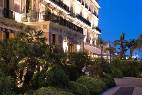 费拉角圣让Hotel Royal-Riviera的一座棕榈树环绕的大建筑