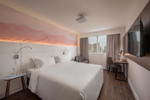 阿雷格里港Intercity Porto Alegre Cidade Baixa的酒店客房设有一张白色大床和电视。