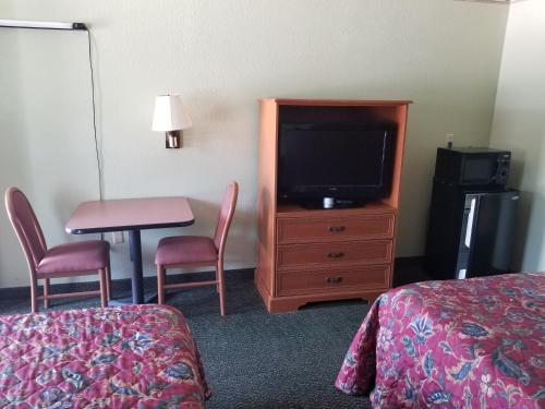 沃思堡沃斯堡霍尔特姆旅馆的酒店客房配有电视、桌子和椅子。