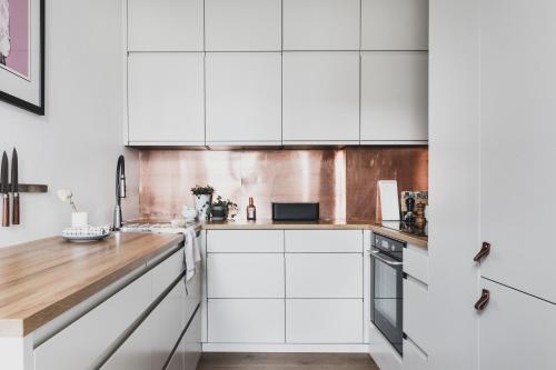 卑尔根Neumannsgate 4的厨房配有白色橱柜和木制台面
