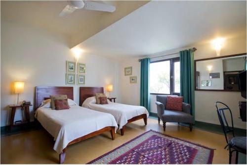 新德里Zaza Stay的一间卧室设有两张床、一把椅子和一个窗户。