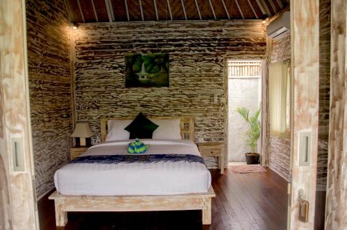 蓝梦岛卡康旅馆的一间卧室设有一张床和石墙