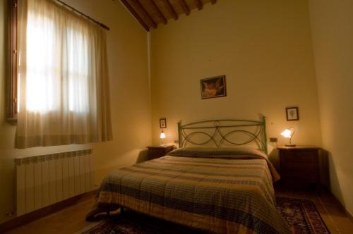 奥贝里塞Tenuta di Alberese的一间卧室配有一张床、一个窗口和两盏灯。