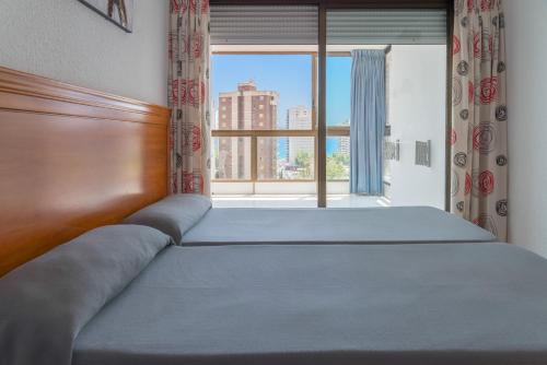 贝尼多姆Gemelos 2 - Beninter All Inclusive的卧室内的一张床铺,设有大窗户
