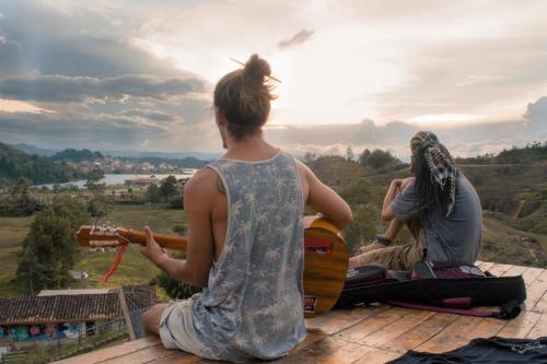 瓜塔佩Casa Kayam Hostal y Residencia Artística的两人坐在屋顶上弹吉他