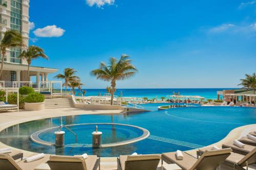 坎昆Sandos Cancun All Inclusive的一个带椅子的游泳池,背景是大海
