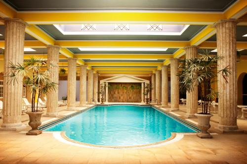 波苏斯-迪卡尔达斯皇宫酒店的一座带柱子和天花板的建筑中的游泳池