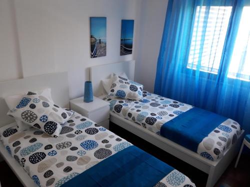 塞图巴尔Apartamento Sado的一间卧室设有两张床和蓝色窗帘