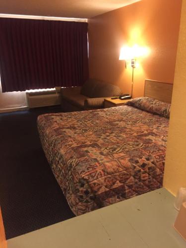 阿马里洛Camelot Inn的配有一张床和一把椅子的酒店客房