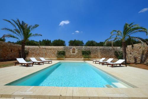 佩斯科勒海滨Relais Masseria Sant'Antonio的一个带躺椅的游泳池以及砖墙
