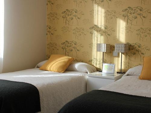 La Pradera de Navalhorno喹啉西亚瓦尔森酒店的壁纸客房内的两张床