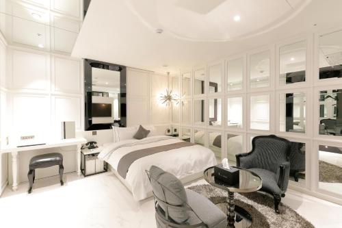龙仁市伊斯基亚酒店的白色卧室配有床、书桌和椅子