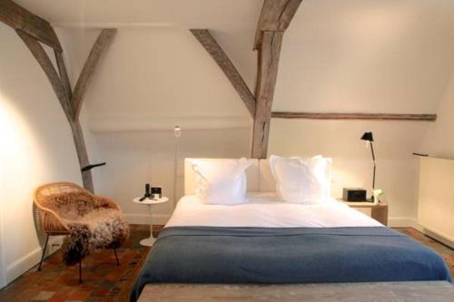 安特卫普朱利安酒店的一间卧室配有一张大床和一把椅子