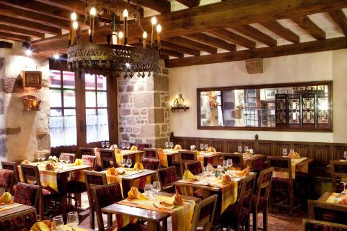 圣米歇尔山奥贝奇圣皮埃尔酒店的餐厅设有木桌、椅子和吊灯。