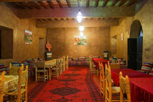 斯库拉Skoura Lodge的一间配备有桌椅的用餐室和红色地毯
