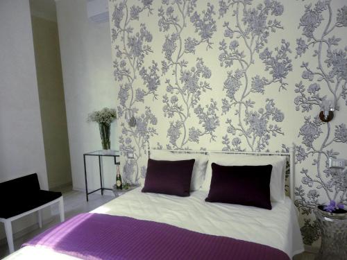 罗马卡梅奥住宿加早餐旅馆的一间卧室配有一张带紫色枕头和壁纸的床