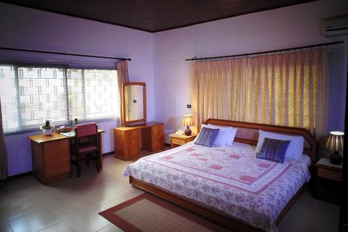 阿克拉Lavender Lodge Hotel的卧室配有一张床、一张书桌和窗户。