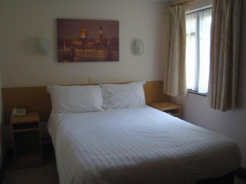 希钦费斯酒店的一间卧室配有一张带白色床单的床和一扇窗户。