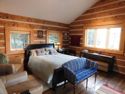 南福克Riverside Meadows Cabins的一间卧室配有一张床、一把椅子和一张沙发