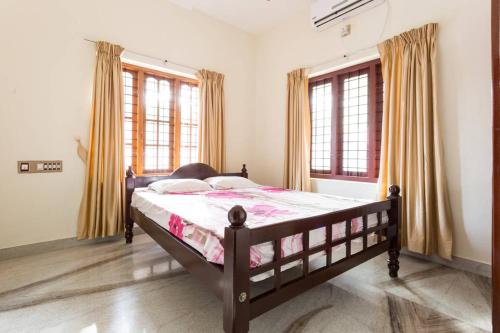 科钦Stay at DBRA 61 Don Bosco Cross Road Vaduthala Ernakulam的一间卧室设有一张床和两个窗户。