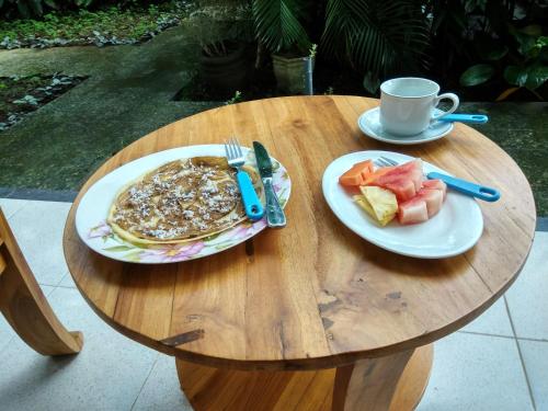 乌布巴厘岛巴提克斯卡尔民宿的一张桌子,上面放着两盘煎饼和一杯咖啡