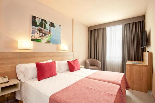坎布里尔斯欧亨尼奥港酒店的酒店客房配有一张带红色枕头的大床