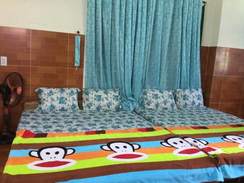 潘郎Nhu Y Guesthouse的一张床上有毯子,上面有猴子的脸