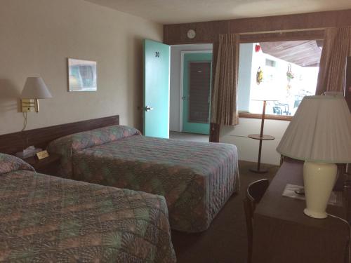 怀尔德伍德Crystal Sands Motel的酒店客房设有两张床、一盏灯和一扇窗户。