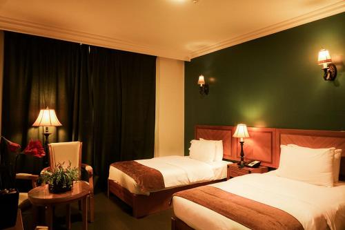 马斯喀特阿曼拉罗莎酒店的酒店客房设有两张床和绿色的墙壁。