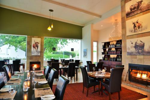 惠灵顿Val Du Charron Wine & Leisure Estate的一间带桌椅和壁炉的餐厅