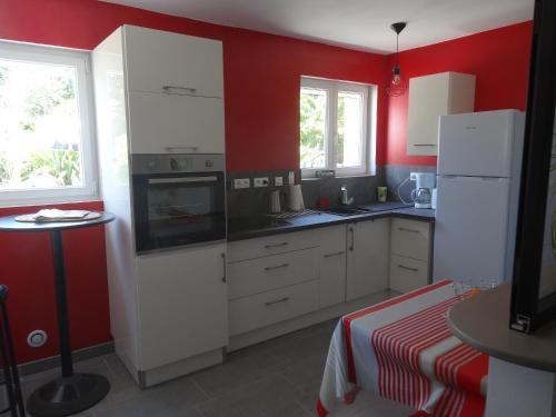 Saint-Aignan-Grand-LieuLe Studio的厨房配有白色橱柜和红色墙壁