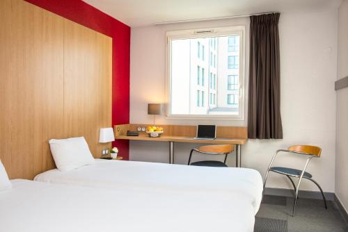 拉罗谢尔B&B HOTEL La Rochelle Centre的配有一张床、一张书桌和一扇窗户的酒店客房