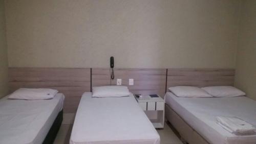 阿拉瓜伊纳Hotel Boiadeiro的一间设有两张床的客房和墙上的一部电话
