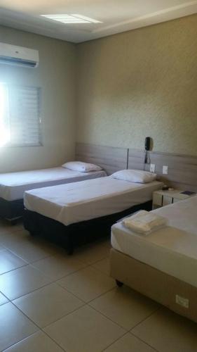 阿拉瓜伊纳Hotel Boiadeiro的一间房间,有三张床