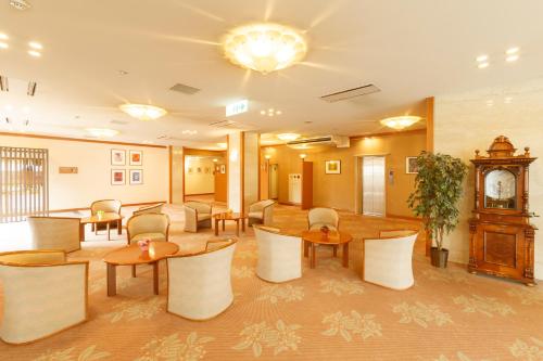 舞鹤市阿玛拜耳舞鹤酒店的大堂设有桌椅和时钟