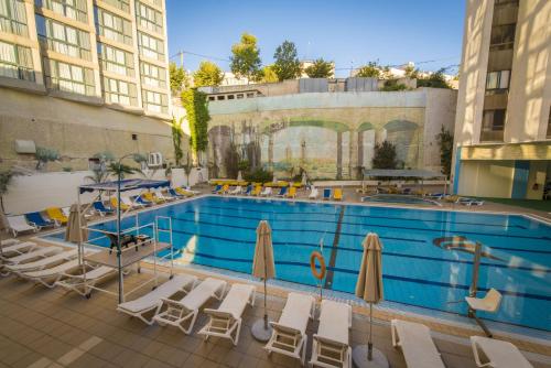耶路撒冷Shalom Jerusalem Hotel的一个带椅子和遮阳伞的大型游泳池
