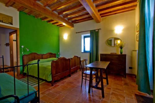 古比奥Agriturismo Foglie的卧室设有绿色墙壁和桌椅