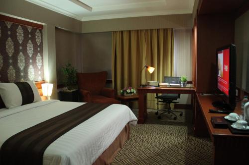 占碑市阿巴迪套房酒店&大厦的配有一张床和一张书桌的酒店客房