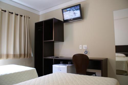 林斯Cristal Palace Inn的客房设有两张床和一张桌子,墙上配有电视。