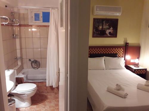 伊奥斯乔拉帕台农酒店的一间卧室配有一张床,浴室设有浴缸