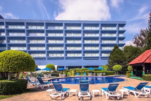 莫雷利亚莫雷利亚格兰贝斯特韦斯特PLUS酒店的一座带椅子的酒店、一座游泳池和一座建筑