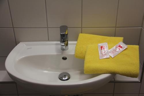 海德堡海德堡国际青年旅馆的浴室水槽设有黄毛巾和水龙头