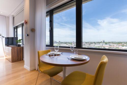 鹿特丹鹿特丹尊贵套房公寓的一间带桌椅和大窗户的用餐室