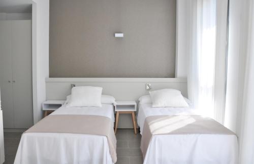 塔拉戈纳Residencia Universitaria Tarragona Mediterrani的白色墙壁的客房内的三张床