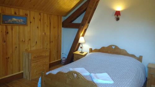圣热尔韦莱班乔利山旅馆的卧室配有一张床铺,位于带木墙的房间内